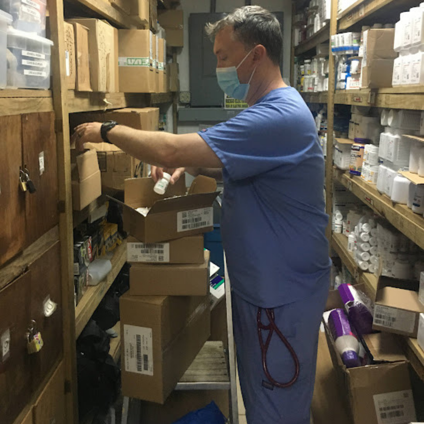 Person organizing or retrieving medical supplies from shelves in a storage room.