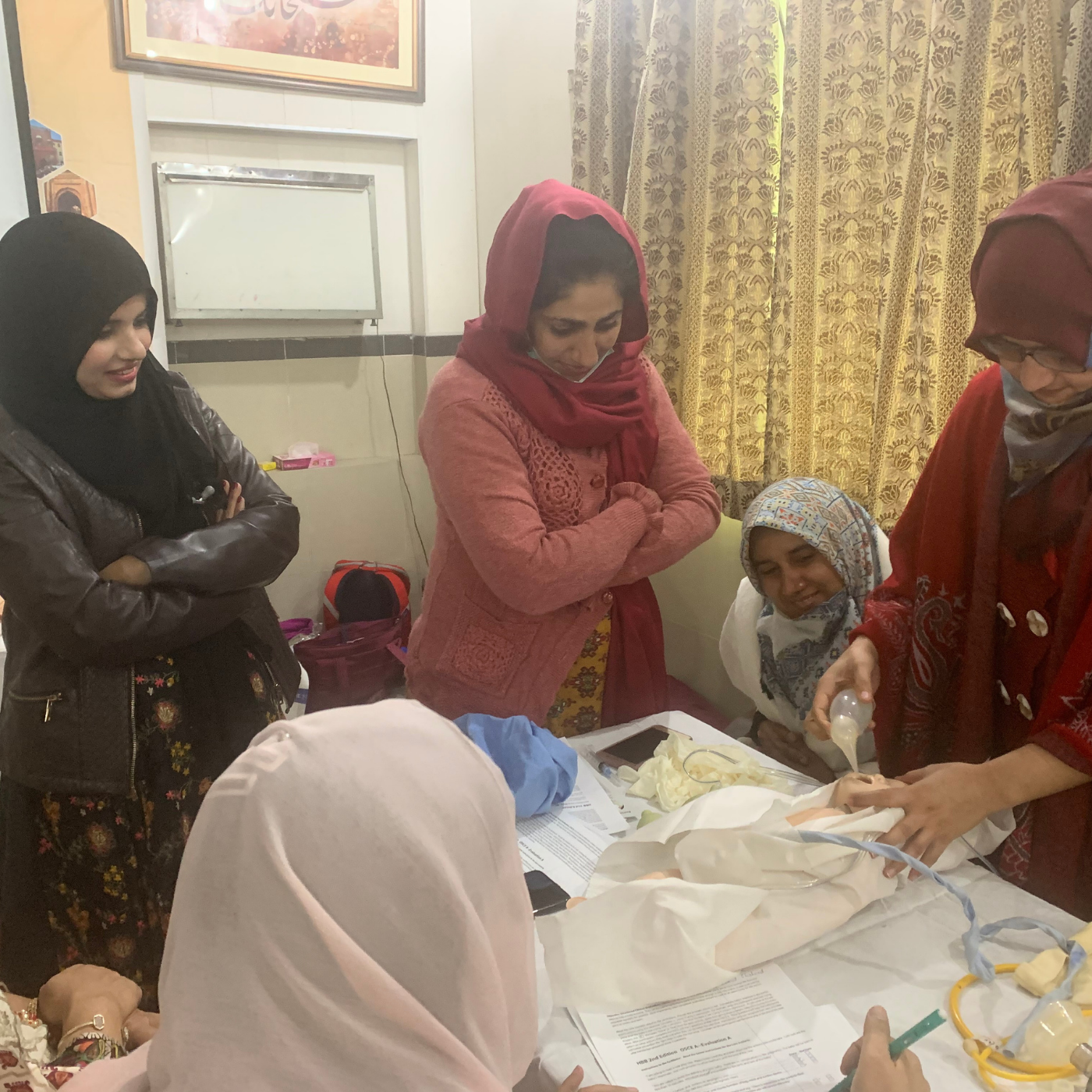 Group of people gathered around a table during a hands-on activity in helping babies breathe.