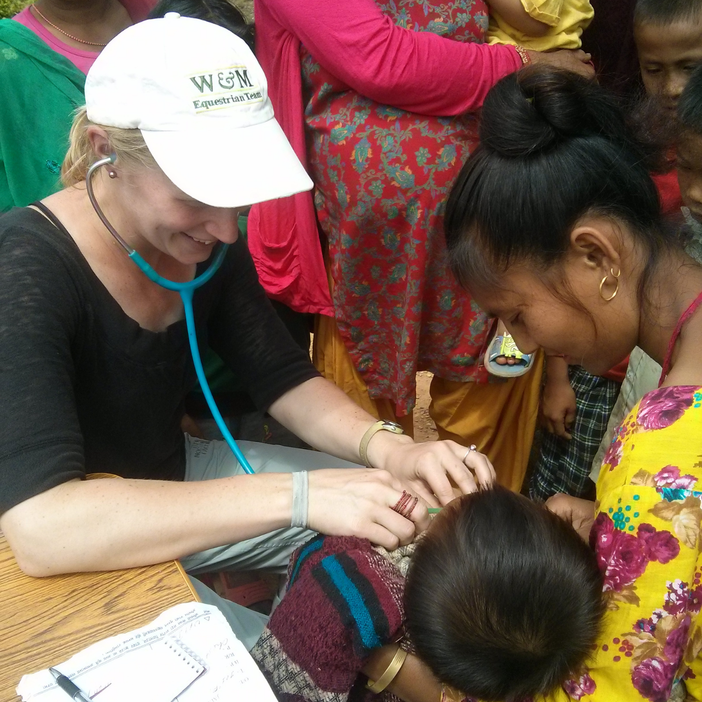 Healthcare professional providing care to a child with children gathered nearby.