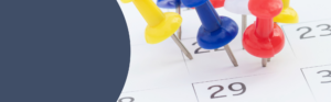 Calendar page marked with colored push pins highlighting important dates.