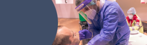 Healthcare professional using protective equipment while providing patient care.
