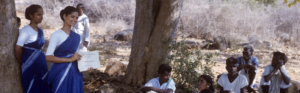 Community health education session taking place in a rural village setting.